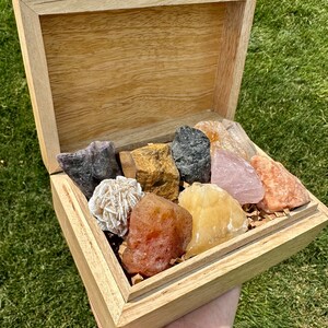 May include: A wooden box filled with a variety of colorful crystals, including rose quartz, amethyst, tiger's eye, and selenite.