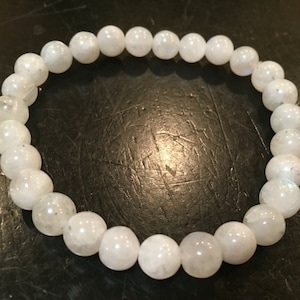 May include: A white moonstone bracelet with round beads. The bracelet is made of natural stones and has a subtle shimmer.
