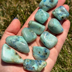 May include: A collection of ten tumbled blue green chrysocolla stones. The stones are smooth and polished, with a variety of shapes and sizes.