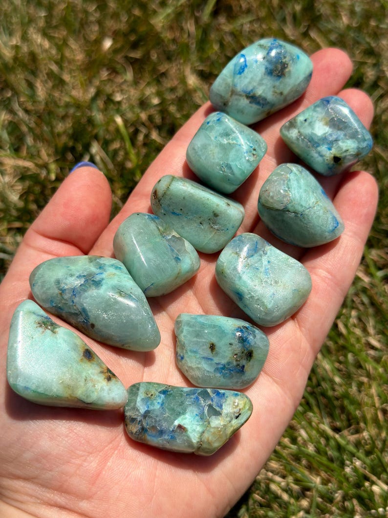 May include: A collection of ten tumbled blue green chrysocolla stones. The stones are smooth and polished, with a variety of shapes and sizes.