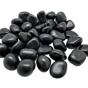 May include: A collection of smooth, black tumbled stones. The stones are various sizes and shapes, and have a polished, glossy finish.