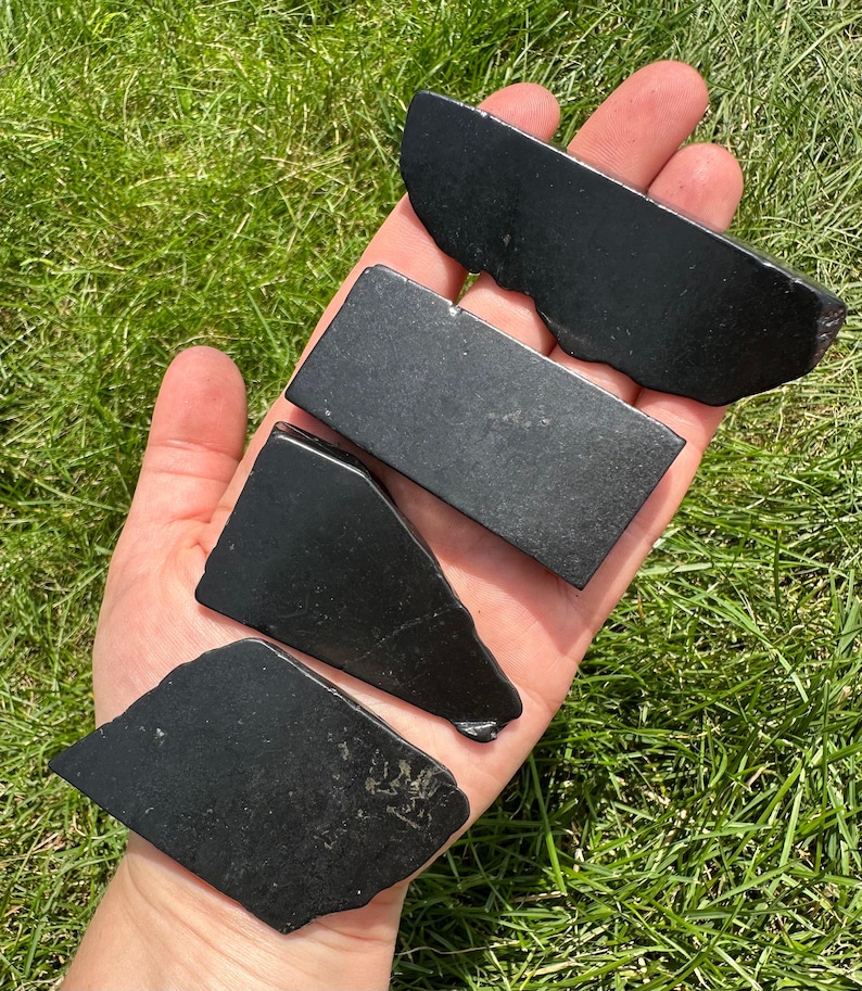 May include: Four black obsidian stones of varying shapes and sizes. The stones are smooth and polished, with a dark, glossy finish.