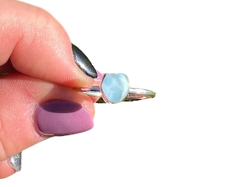 May include: A silver ring with a light blue gemstone. The gemstone is a freeform shape and has a slightly cloudy appearance.