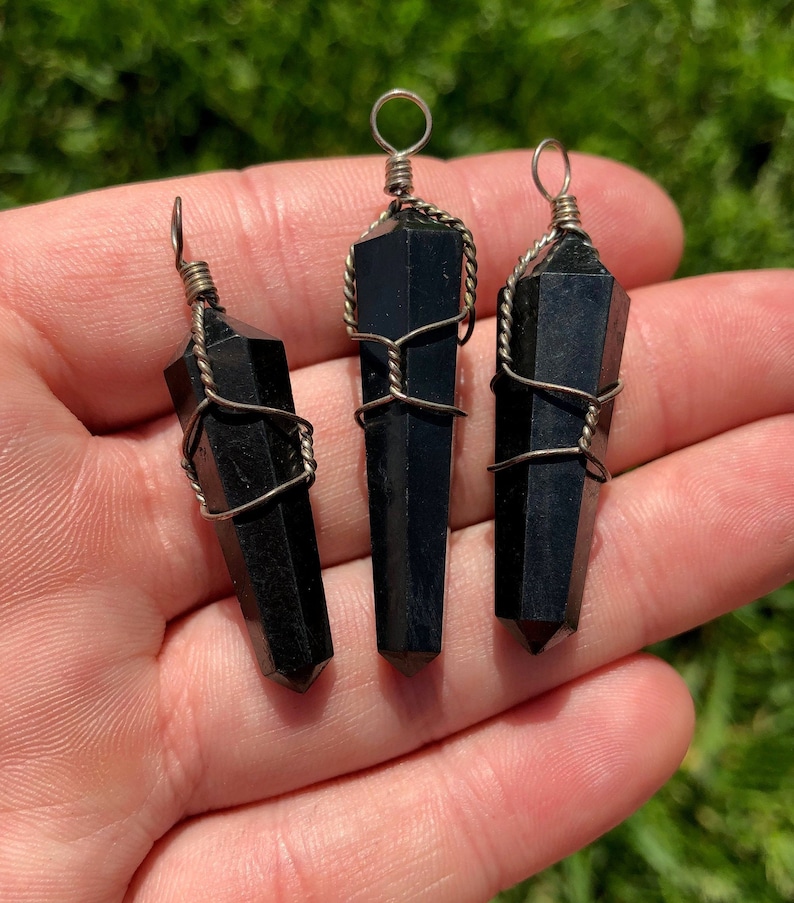 Pode incluir: Tr&ecirc;s pingentes de ponta de cristal de obsidiana preta envoltos em fio de prata. Cada pingente tem um la&ccedil;o na parte superior para prender a um colar ou pulseira.