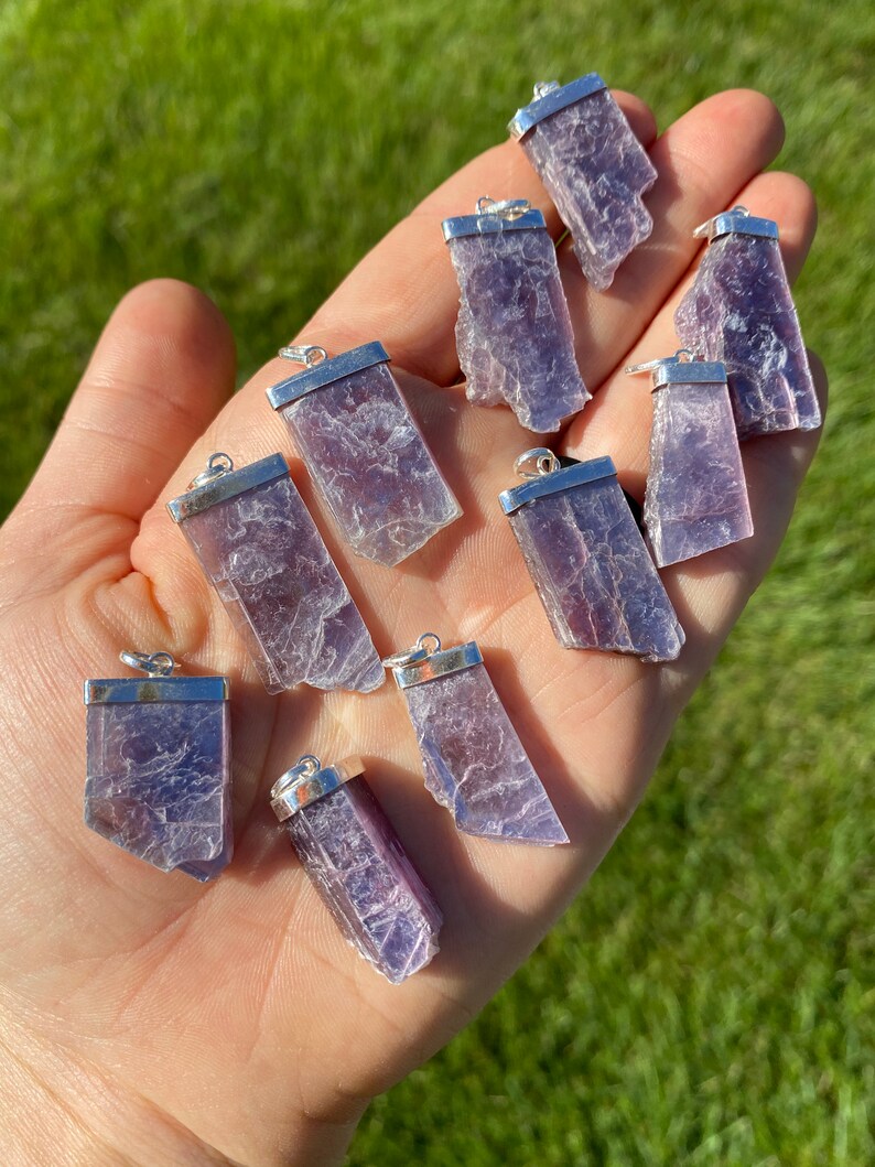 May include: Ten purple lepidolite crystal pendants with silver bail settings. The pendants are various shapes and sizes.