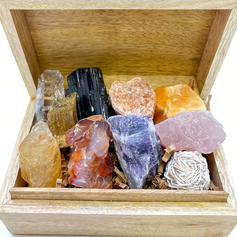 May include: A wooden box filled with a variety of crystals, including clear quartz, amethyst, rose quartz, citrine, carnelian, tiger's eye, and black tourmaline.