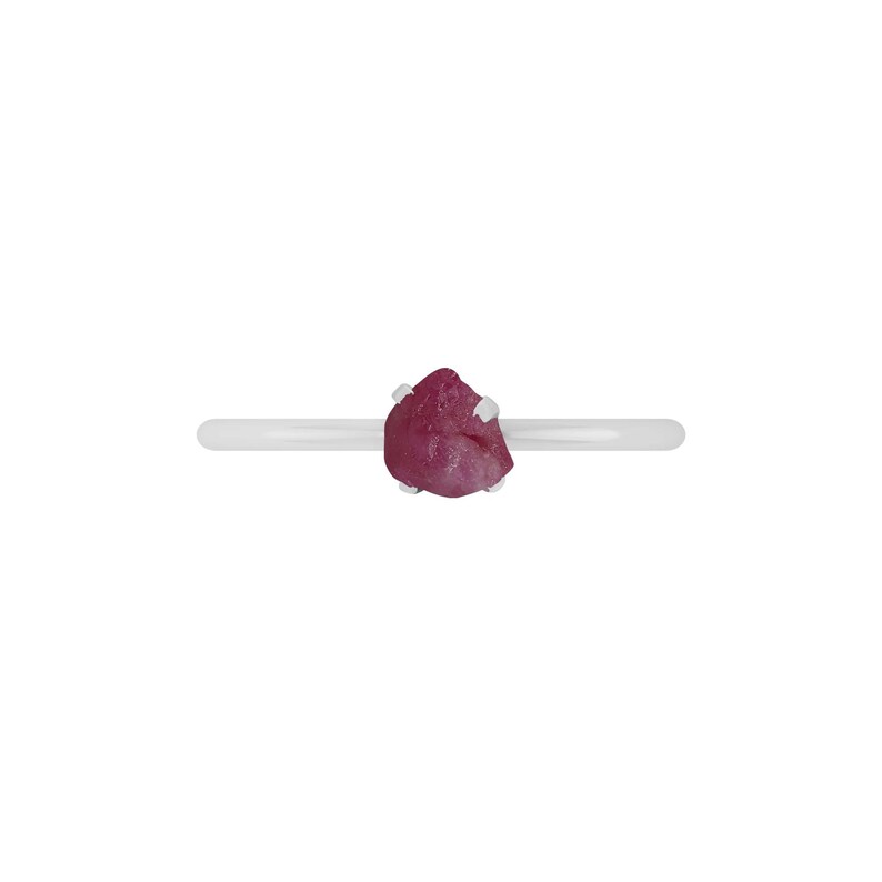 May include: A silver ring with a pink, rough-cut gemstone.