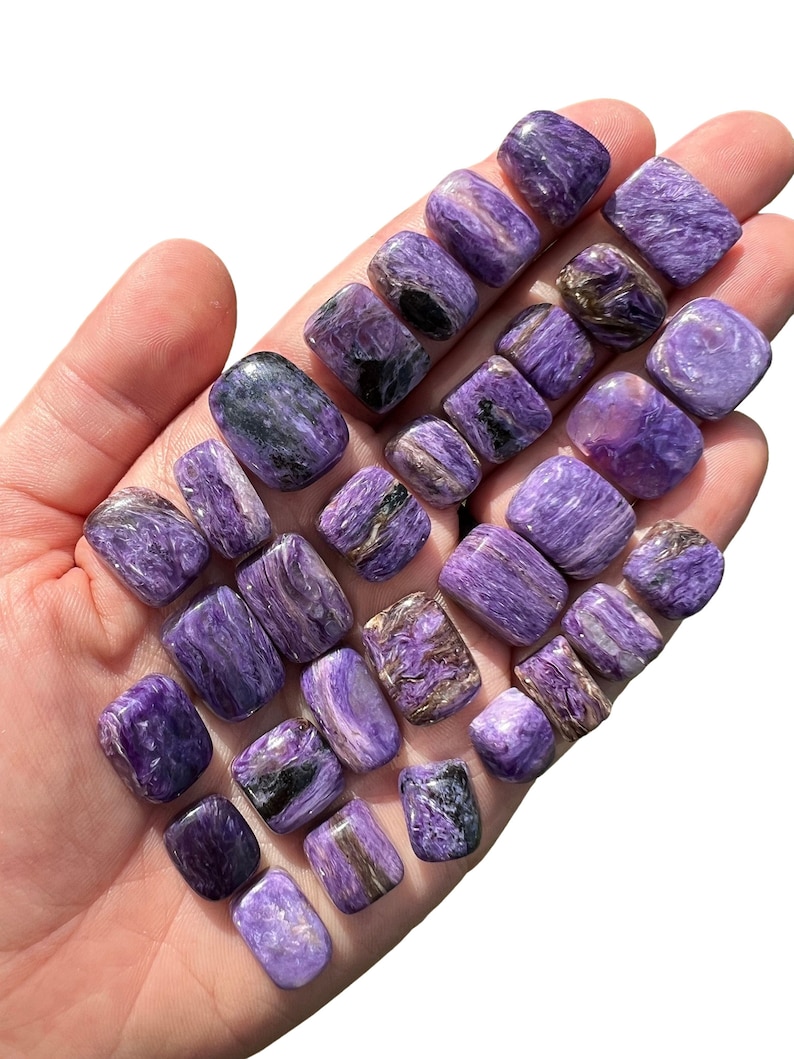 May include: A collection of 20 tumbled purple and black spectrolite stones. The stones are smooth and polished, with a variety of patterns and swirls.