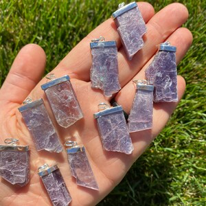 May include: A collection of 12 silver-plated lepidolite crystal pendants. The pendants are all different shapes and sizes, but they are all a beautiful shade of purple.