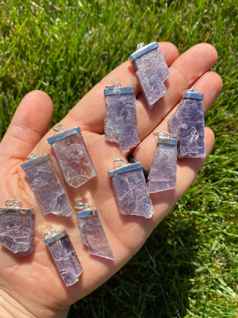 May include: A collection of 12 silver-plated lepidolite crystal pendants. The pendants are all different shapes and sizes, but they are all a beautiful shade of purple.