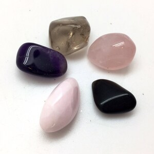 Puede incluir: Cinco piedras pulidas en varios colores, incluyendo amatista, cuarzo rosa, cuarzo ahumado, cuarzo transparente y obsidiana negra.