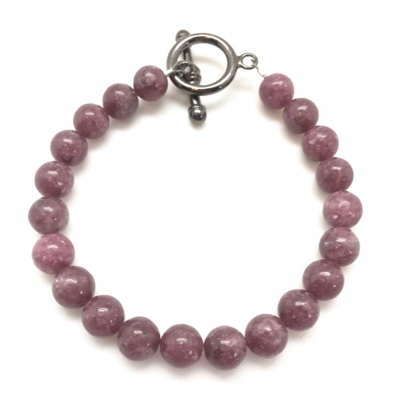 K&ouml;nnte beinhalten: Ein Armband aus rosafarbenen Lepidolith-Perlen mit einem silbernen Toggle-Verschluss.