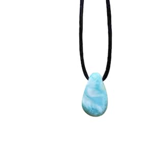 May include: A teardrop-shaped blue and white gemstone pendant on a black cord necklace.