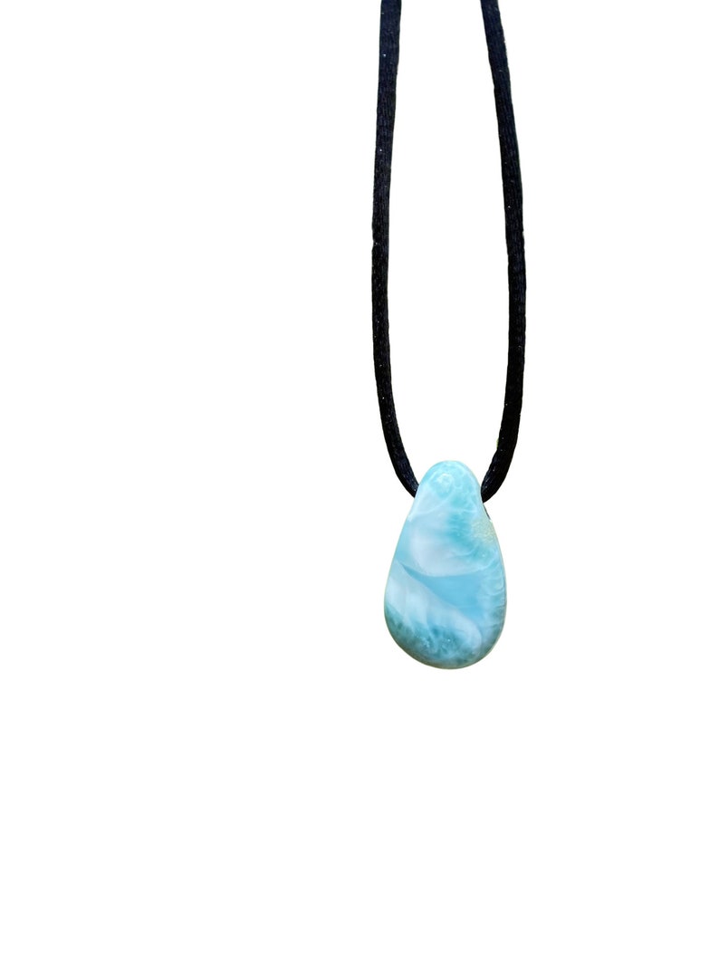 May include: A teardrop-shaped blue and white gemstone pendant on a black cord necklace.