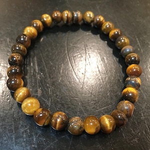 May include: A brown and gold beaded bracelet made of tiger's eye stones.