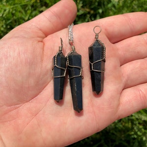 Pode incluir: Tr&ecirc;s pingentes de cristal de obsidiana preta envoltos em fio de prata. Os pingentes s&atilde;o de tamanhos diferentes e est&atilde;o pendurados em correntes de prata.