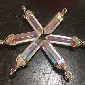 May include: Six iridescent crystal point pendants with silver settings. The points are clear with a rainbow sheen.
