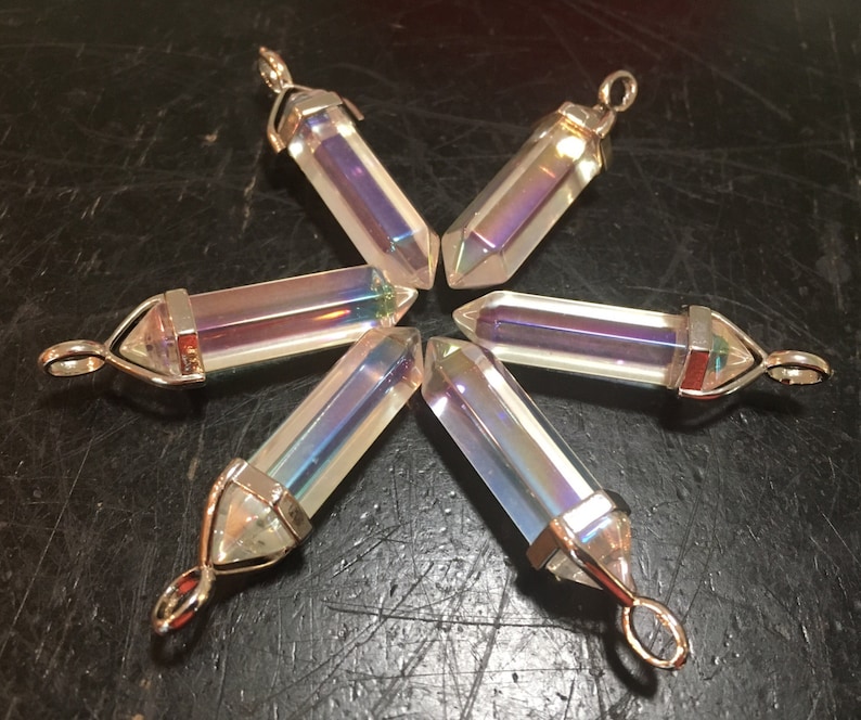 May include: Six iridescent crystal point pendants with silver settings. The points are clear with a rainbow sheen.