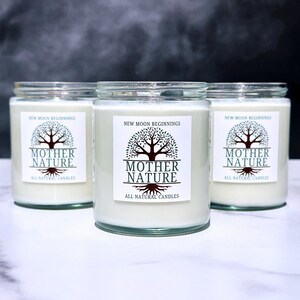 May include: Three glass candle jars with white labels. The labels have a tree design and the text "NEW MOON BEGINNINGS" and "MOTHER NATURE" with the words "ALL NATURAL CANDLES" below.