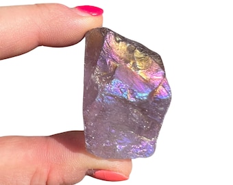 May include: A large, iridescent purple amethyst crystal with a rough, natural shape. The crystal has a rainbow sheen and is a beautiful example of this popular gemstone.