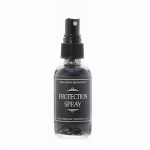 May include: A clear glass spray bottle with a black cap and a black label. The label reads "New Moon Beginnings" and "Protection Spray". The bottle contains a dark liquid and small black stones. The bottom of the label reads "Pure Organic Essential Oils".