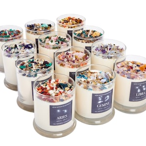 May include: Twelve glass candle jars with a white wax base and a variety of crystals and herbs inside. Each jar has a label with a zodiac sign and the text "New Moon Beginnings" and "All Natural Candles".