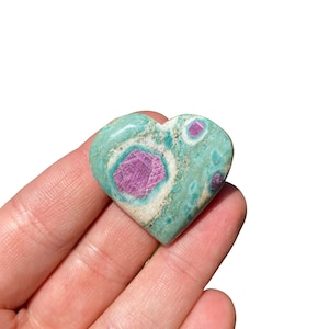May include: A heart-shaped green and pink ruby zoisite crystal. The crystal has a swirling pattern of green, white, and pink.