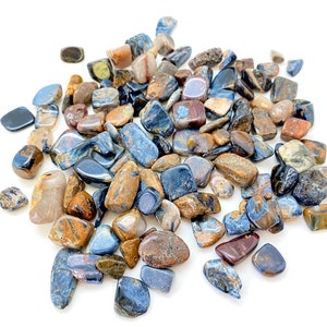 May include: A collection of blue, brown, and gold tiger's eye tumbled stones. The stones are smooth and polished, and they have a variety of shapes and sizes.