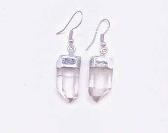 Puede incluir: Un par de pendientes de plata con colgantes de cristal transparente. Las puntas de cristal son facetadas y tienen una tapa de plata en la parte superior.