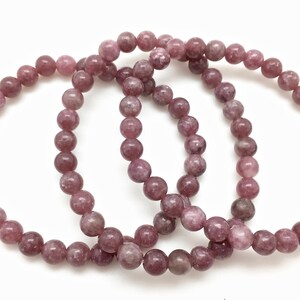 Puede incluir: Tres pulseras de piedra de lepidolita rosa con cuentas redondas.