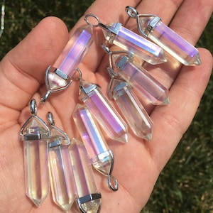 May include: A collection of iridescent clear quartz crystal pendants with silver-toned metal bails. The crystals are faceted and have a rainbow sheen.