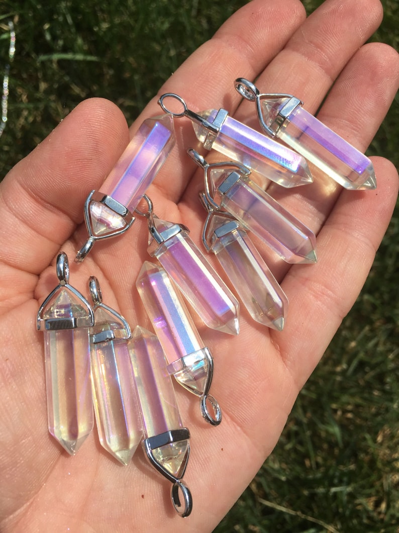 May include: A collection of iridescent clear quartz crystal pendants with silver-toned metal bails. The crystals are faceted and have a rainbow sheen.