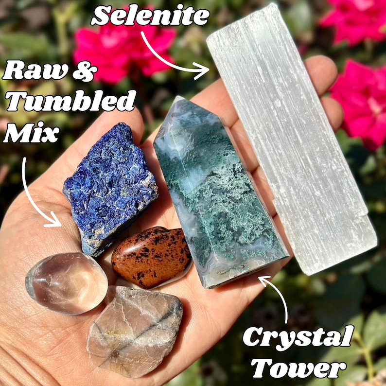 May include: A hand displays a collection of raw and tumbled crystals, including a blue azurite, a brown stone, and a clear quartz. A green and white crystal tower and a white selenite wand are also shown. The text reads "Selenite", "Raw & Tumbled Mix", and "Crystal Tower".