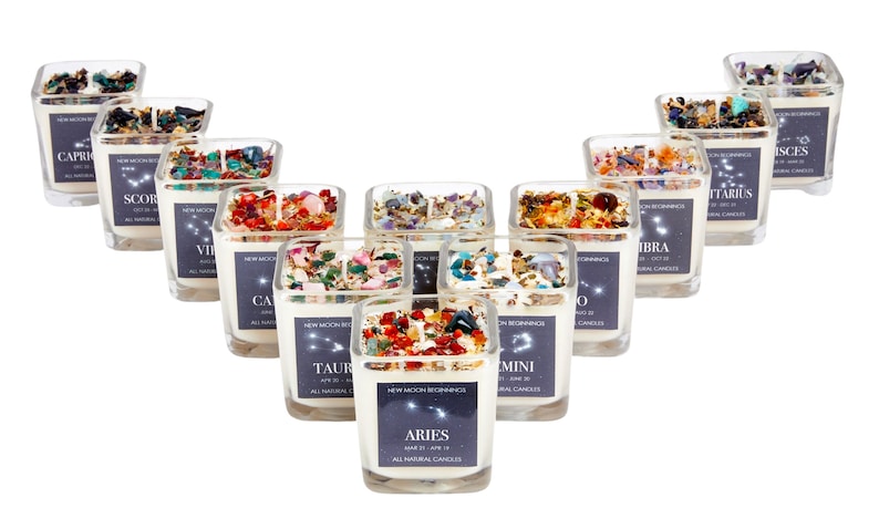 May include: Twelve glass candle jars with white wax and crystals inside. Each jar has a label with a zodiac sign and the dates for that sign. The signs are Aries, Taurus, Gemini, Cancer, Leo, Virgo, Libra, Scorpio, Sagittarius, Capricorn, Aquarius, and Pisces.