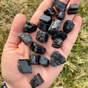 May include: A collection of black tourmaline crystals, also known as schorl, in various sizes and shapes. The crystals are raw and have a natural, rough texture.