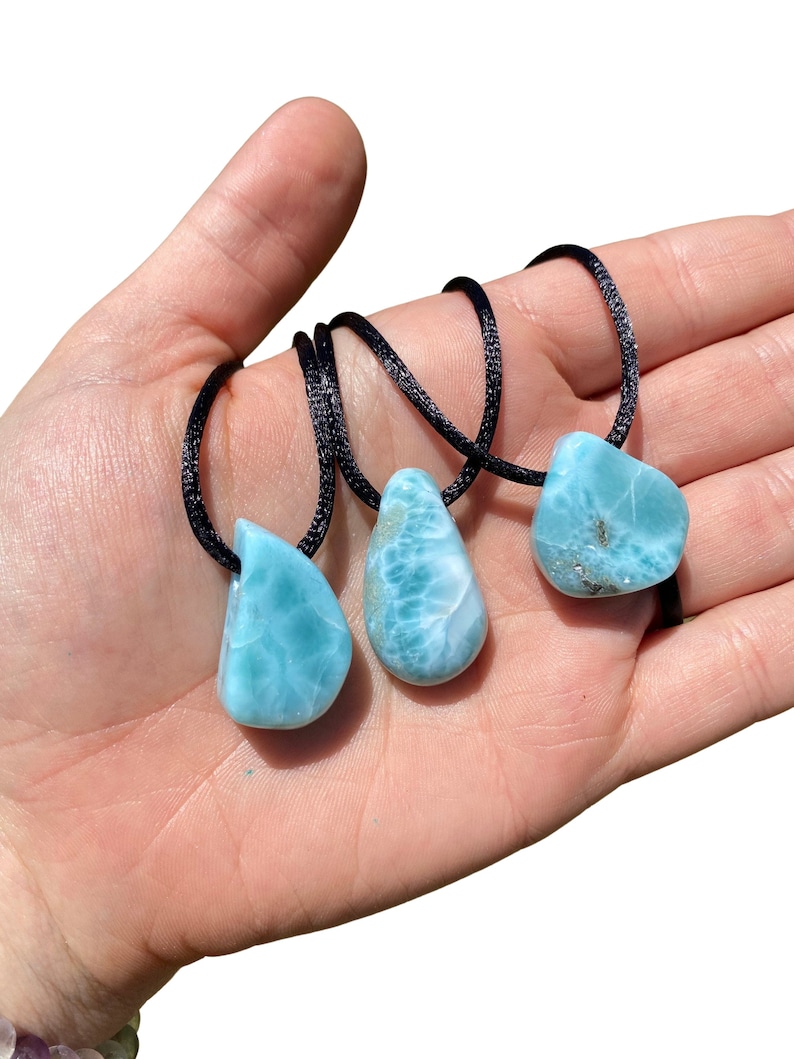 May include: Three teardrop-shaped blue and green gemstone pendants on black cords. The pendants are made of blue and green larimar.
