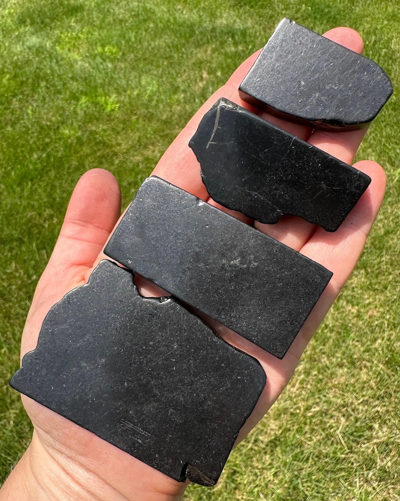 May include: Four black obsidian stones of varying sizes and shapes. The stones are smooth and polished.