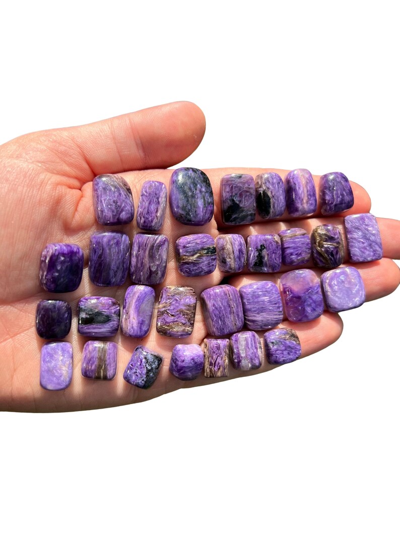 May include: A collection of 20 tumbled purple and silver spectrolite stones. The stones are smooth and polished, with a variety of shapes and sizes.