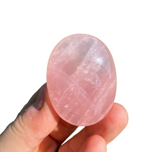 Pu&ograve; includere: Un cristallo di quarzo rosa liscio di forma ovale, di colore rosa pallido e con striature visibili.