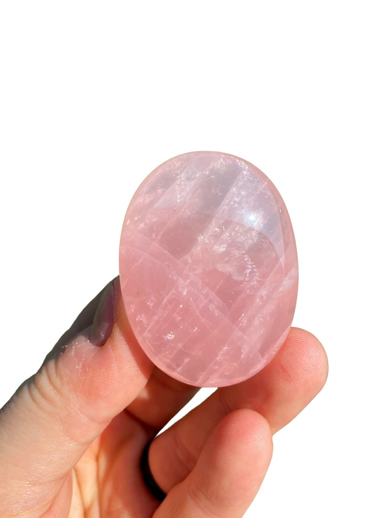 Pu&ograve; includere: Un cristallo di quarzo rosa liscio di forma ovale, di colore rosa pallido e con striature visibili.