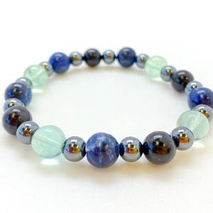 May include: A blue, green, and black beaded bracelet with a variety of gemstone beads.