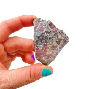 以下が含まれることがあります： 赤、緑、紫の色合いの混ざった、不規則な形の粗い岩。岩は、小さな緑と赤の斑点が散らばった斑点模様をしている。