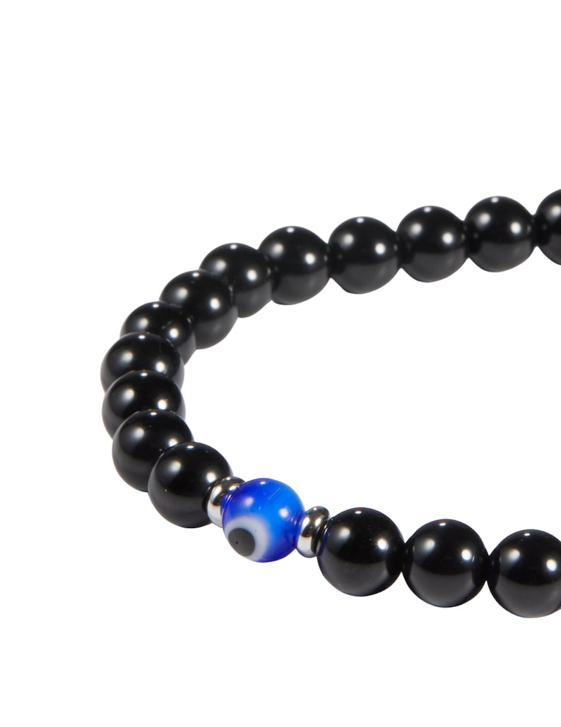 May include: Black beaded bracelet with a single blue eye bead. The bracelet features glossy, round black beads and a central blue bead with a white and black eye design. The bracelet is strung on a flexible cord.