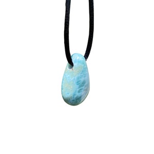 May include: A blue and green gemstone pendant on a black cord necklace.
