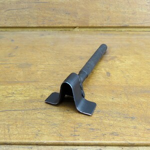 May include: A black metal tool with a handle and a V-shaped base. The tool is designed for bending metal.