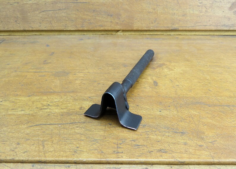 May include: A black metal tool with a handle and a V-shaped base. The tool is designed for bending metal.