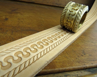 May include: A close-up of a leather strip with a decorative pattern embossed into it. A brass tool with a similar pattern is shown rolling across the leather.