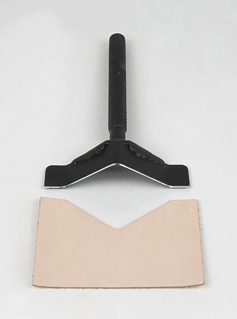May include: A black leather crafting tool with a V-shaped metal blade and a handle. The tool is used to create a V-shaped cut in leather.