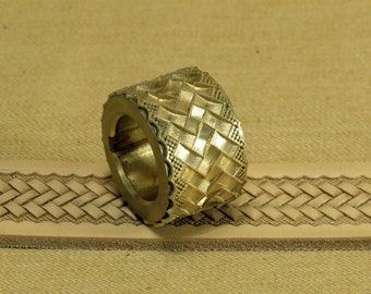 May include: A brass leather stamping tool with a woven pattern. The tool is designed to create a raised, textured design on leather.