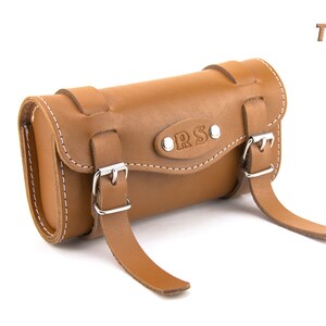 May include: Tan leather bicycle handlebar bag with two buckles and the word "ORS" embossed on the front.